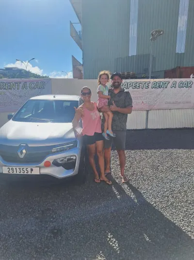 Famille avec enfant devant une Renault Kwid grise