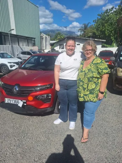 Deux clientes souriantes devant une Renault Kwid rouge
