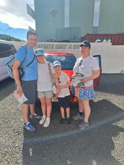 Famille de quatre devant une Renault Kwid rouge à l'agence